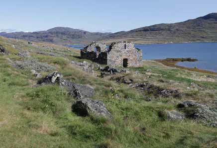 Die steinerne Kirchenruine von Hvalsey auf einer Wiese über dem Fjord