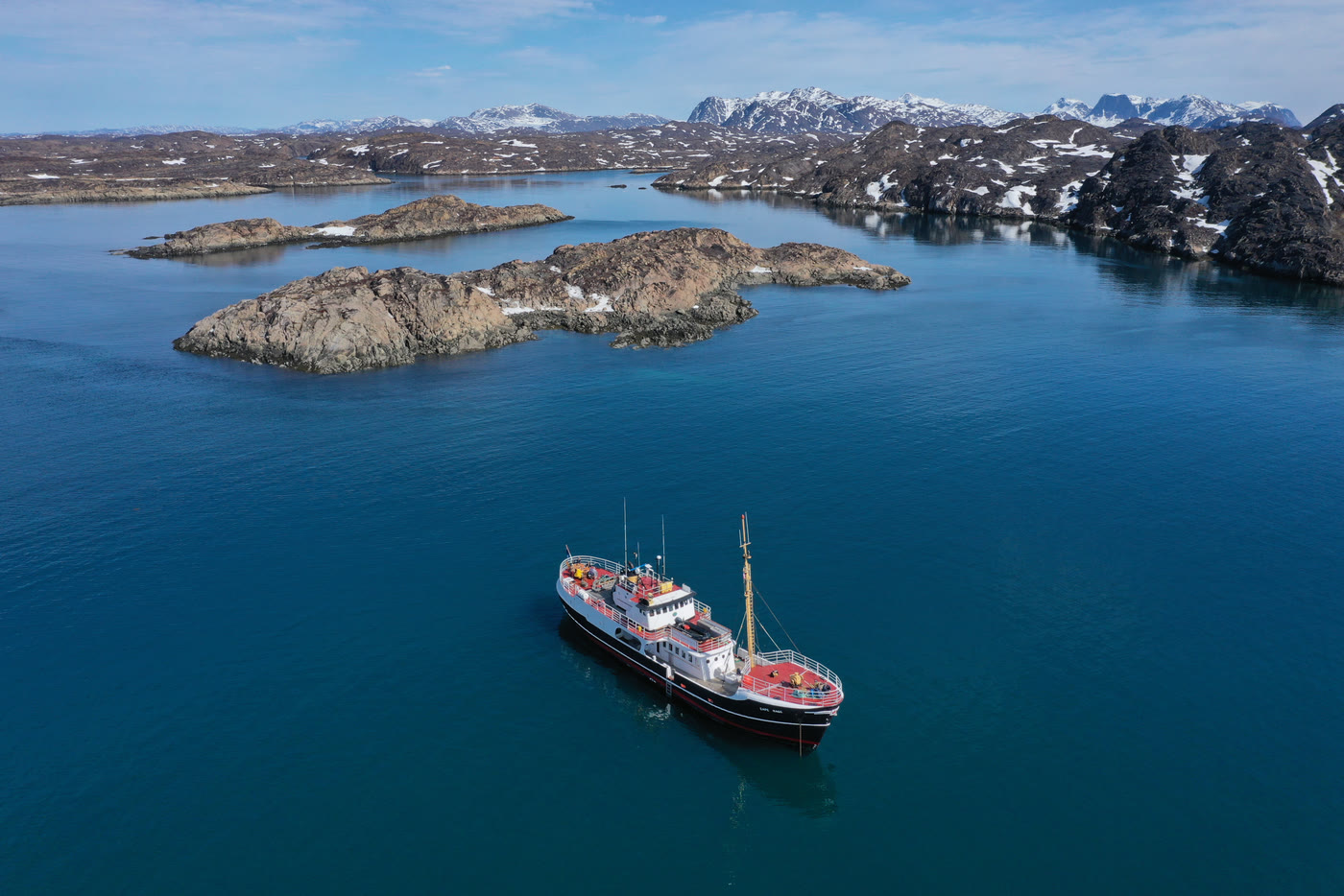 Die MS Cape Race aus der Luft zwischen Schäreninseln in türkisem Wasser