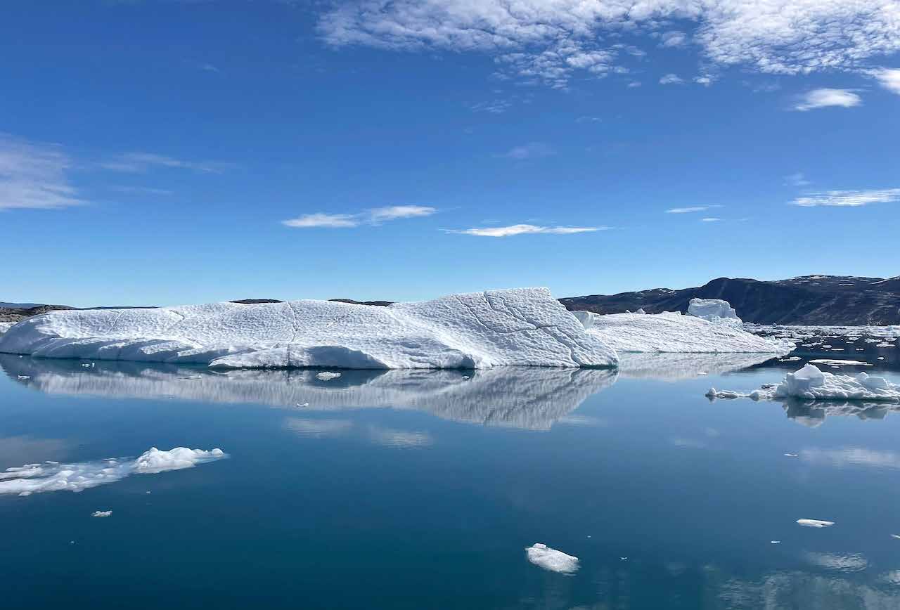 Langgestreckter Eisberg, der sich auf vollkommen glattem Wasser spiegelt