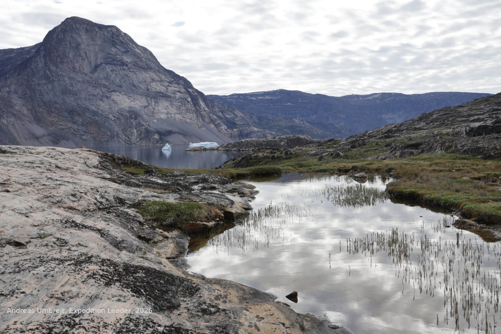 Wolkenhimmel spiegelt sich in einem stillen Bergsee an einer neuen Wanderroute in Westgrönland