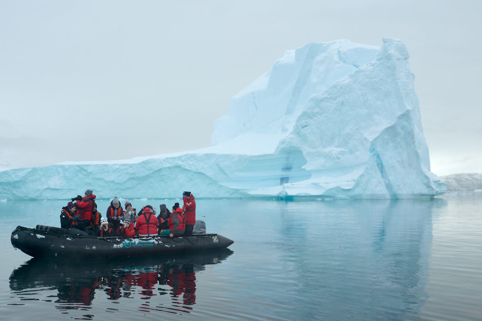 Zodiac mit Gästen vor einem Eisberg im Scoresbysund — Ostgrönland