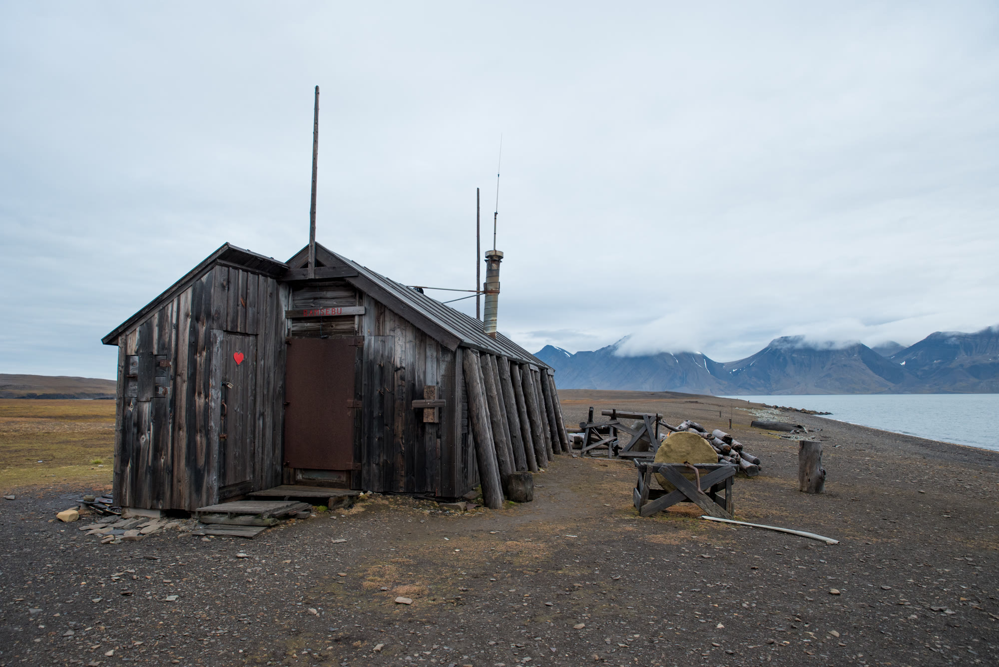 Alte hölzerne Trapperhütte auf Spitzbergen mit Schlitten davor