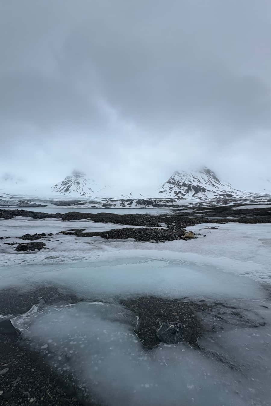 Eiskante und verschneite Berghänge im Nebel, Spitzbergen im Mai