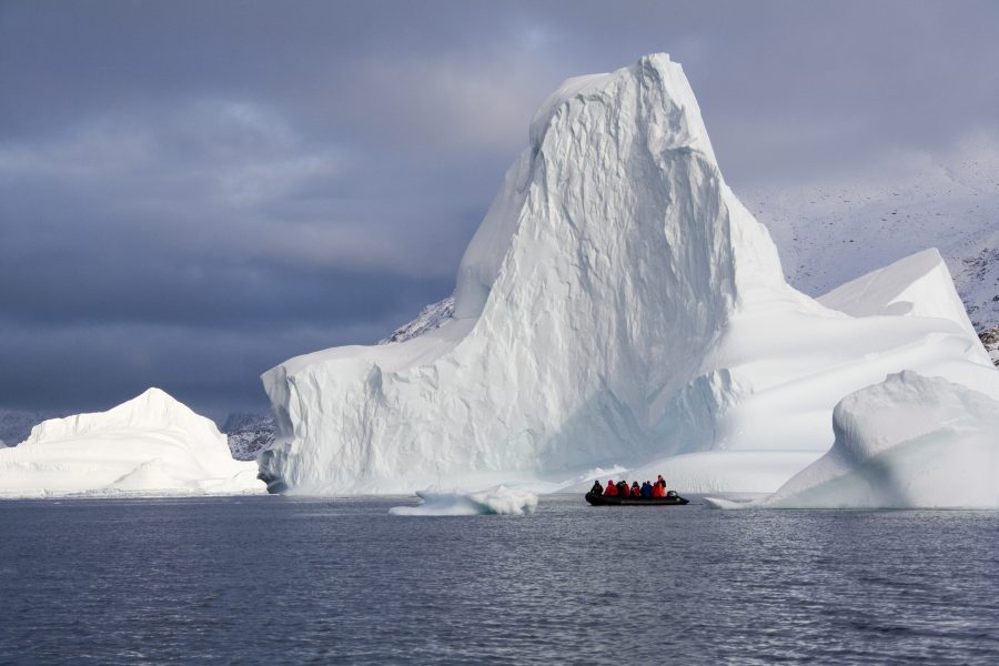 Zodiac vor einem hoch aufragenden Eisberg in Ostgrönland