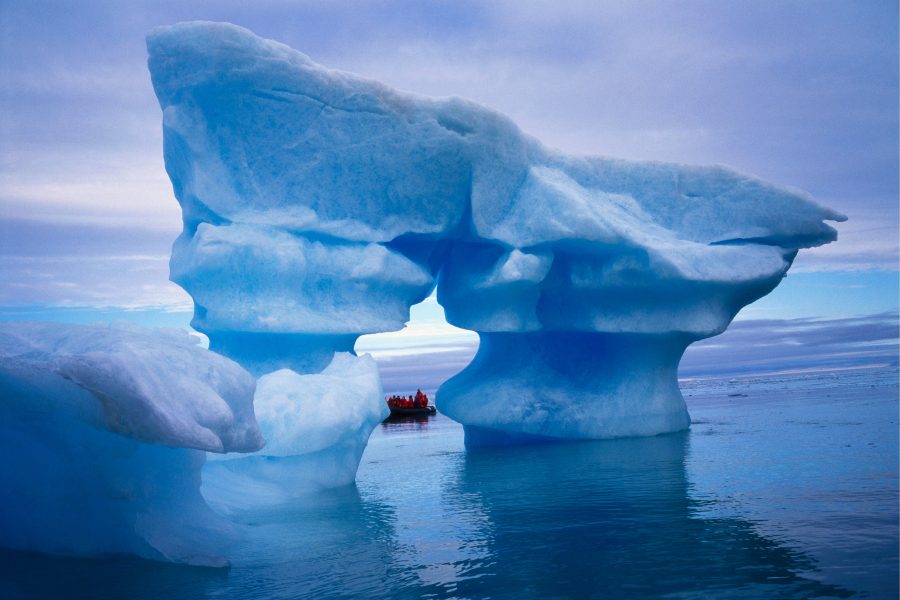 Zodiac hinter einem mächtigen blauen Eisbogen vor Spitzbergen